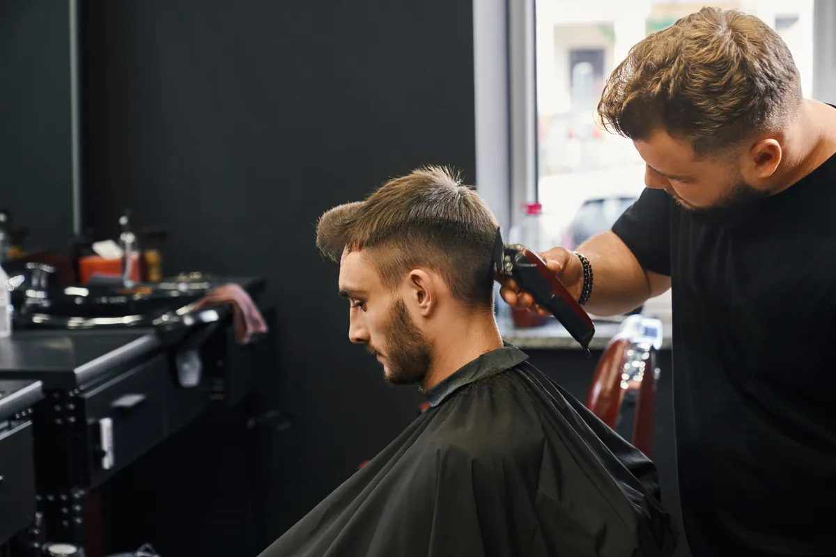 A barber trimming a client’s hair in a salon chair