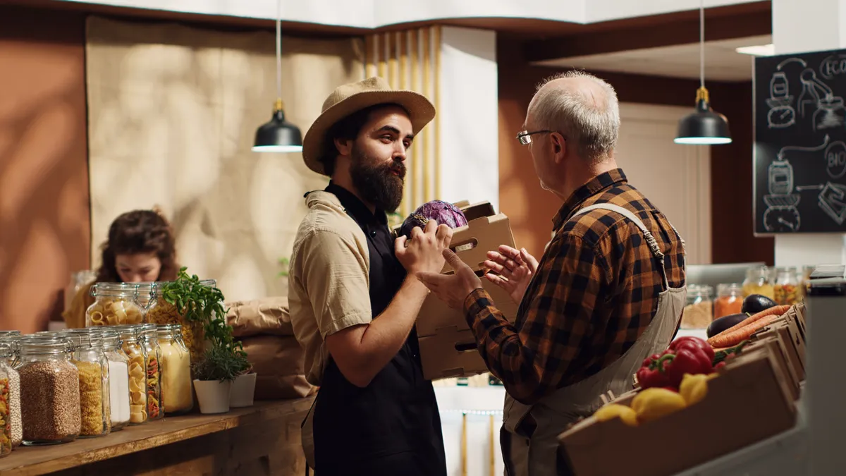 A shopkeeper taking a delivery over the counter of an independent grocery shop