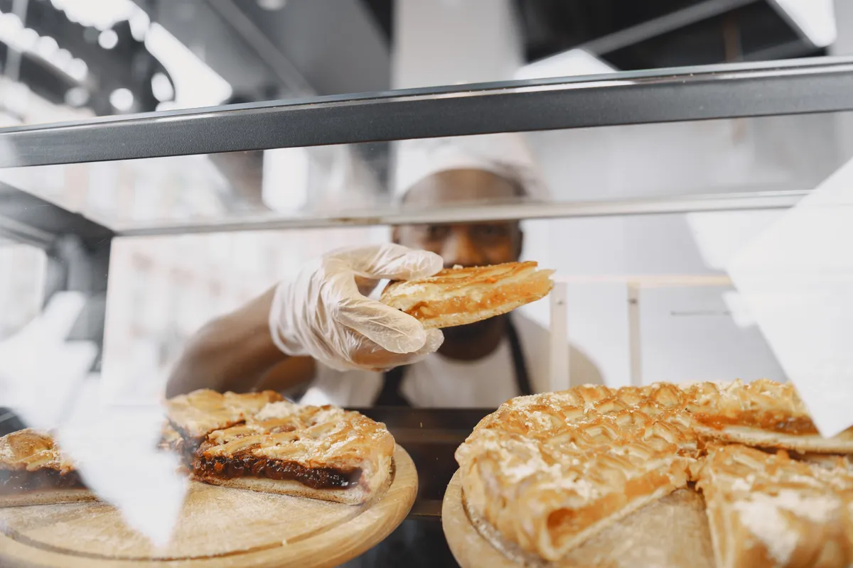 A baker serving a customer over a bakery counter